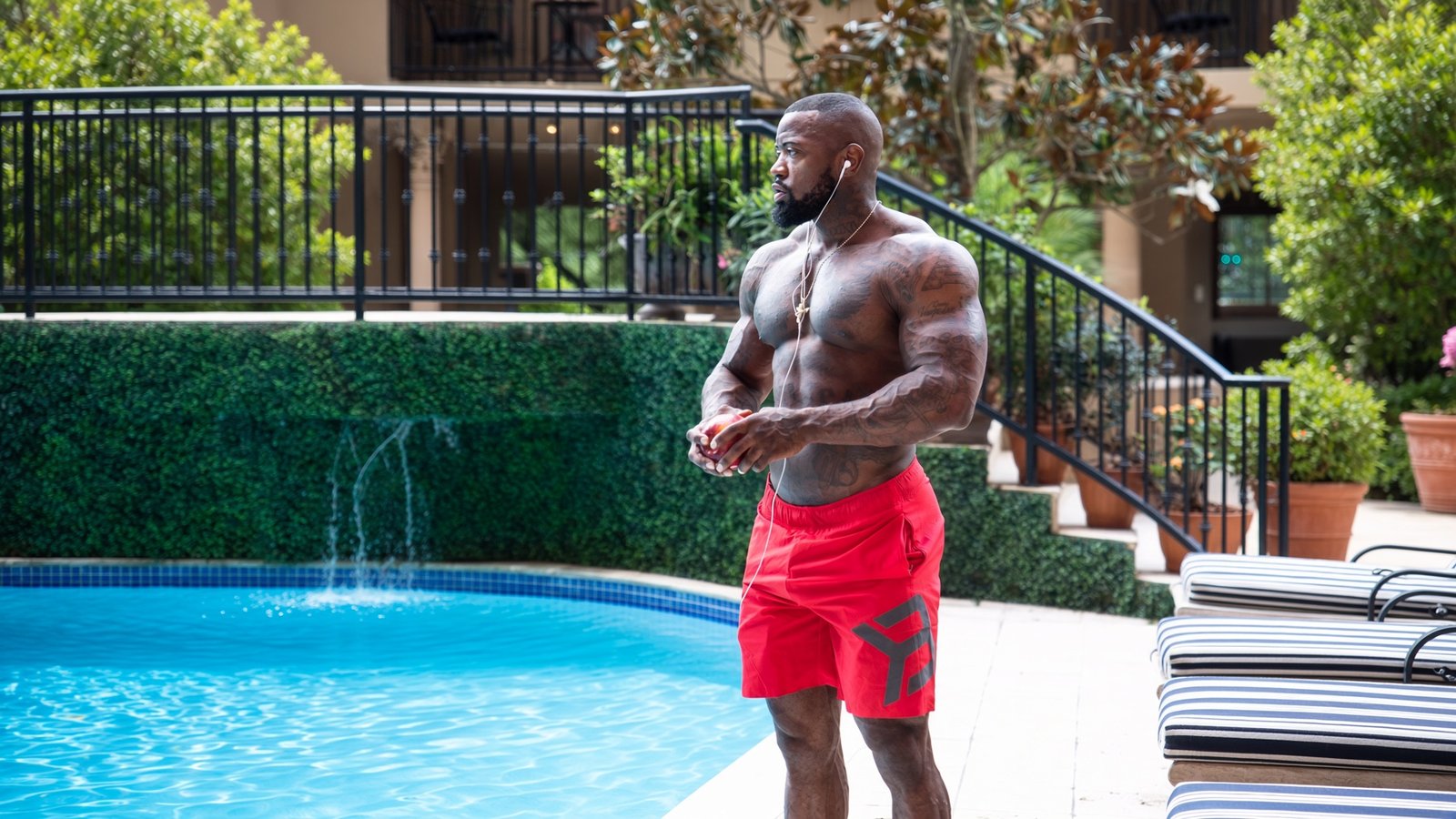 Mike Rashid standing beside a swimming pool in red training shorts.